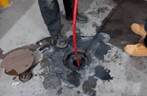 Sewer maintenance is underway with a red hose snaked down a drain