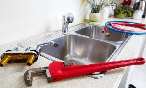 Wrench and Other Materials on a Sink Ledge